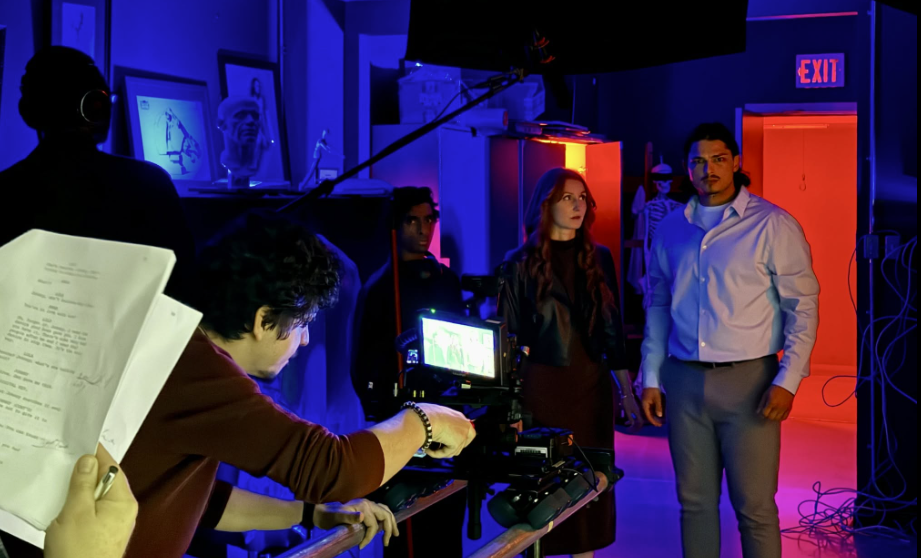 Andres checking the monitor on a moody blue and red lit narrative set.